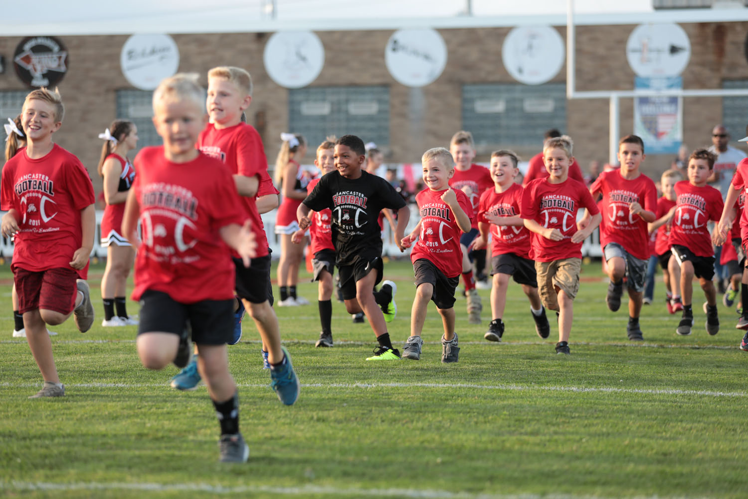 Lancaster Youth Football players with big smiles running onto Foyle-Kling Field